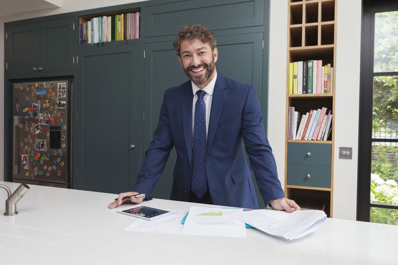 A smiling financial advisor with a digital tablet and paperworks.