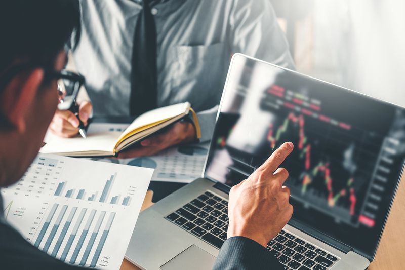 Midsection View of Businessmen Analyzing Charts on Laptop in Office