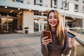 Woman paying with a credit card on her phone outside of a building
