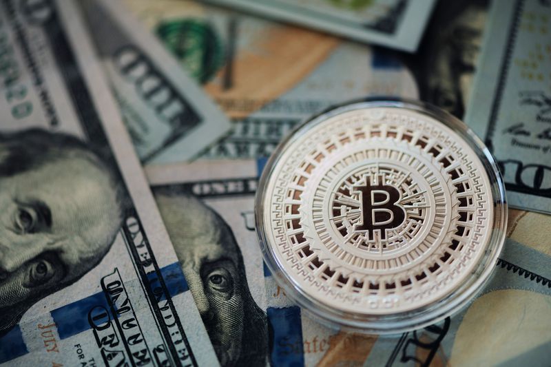 A Bitcoin token and U.S. banknotes.