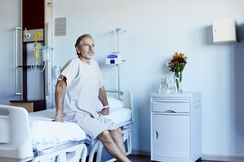 Mature man sitting on bed in bright hospital room