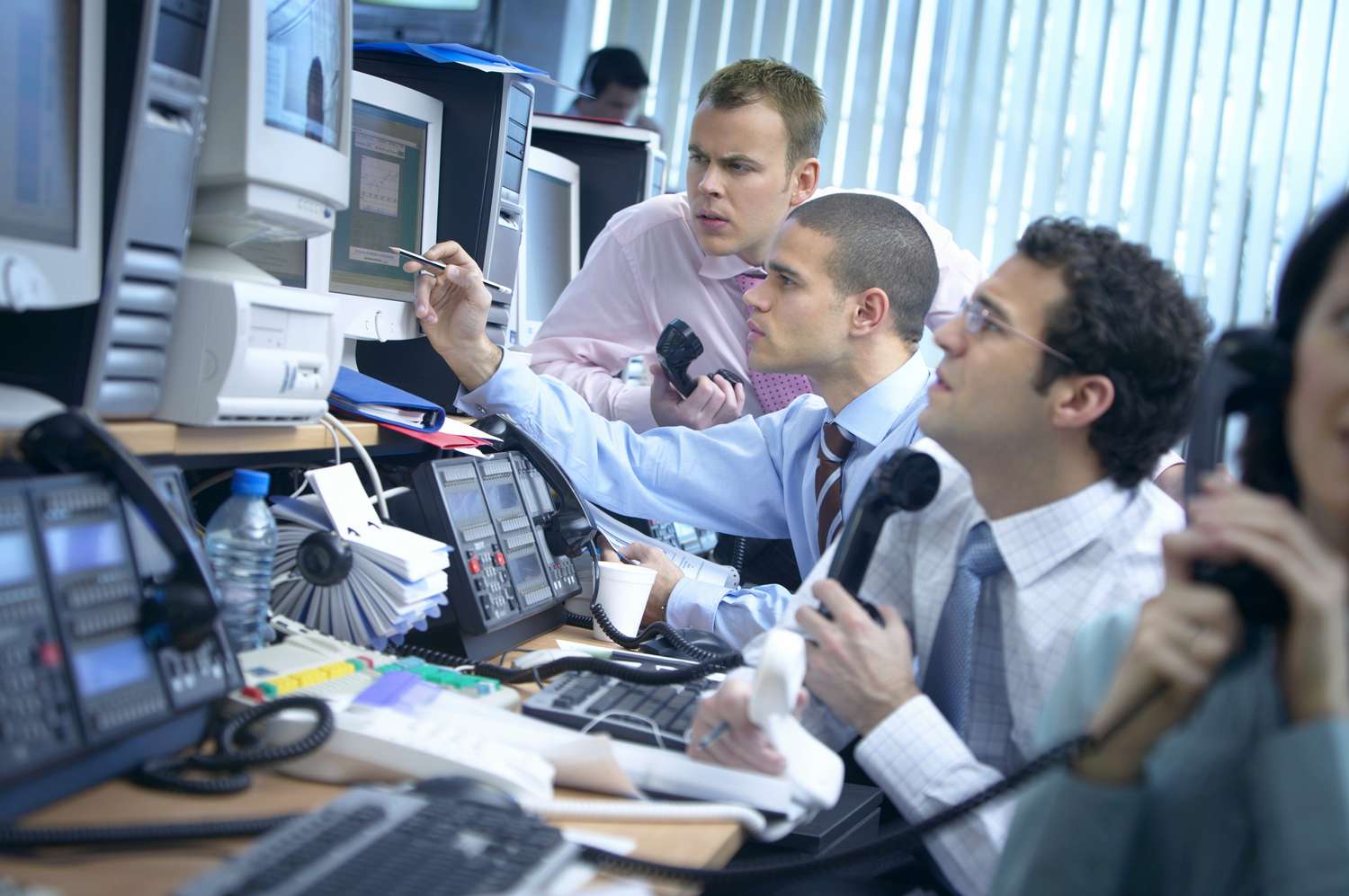 A group of day traders at a busy order desk analyse ways to exploit the Nasdaq trading system for more profit.