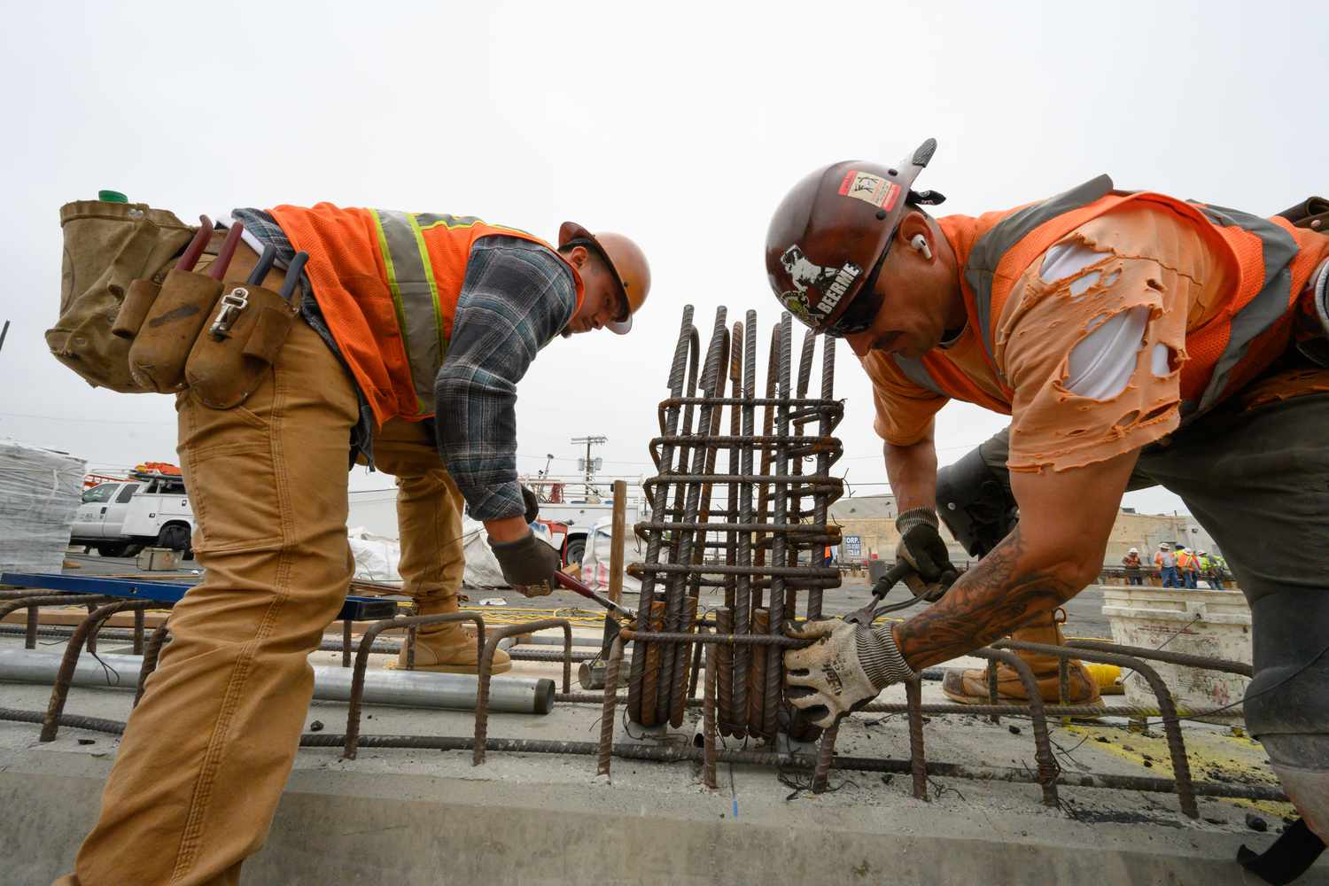 Two rodbuster ironworkers use pliers to attach rebar during the construction of the new 6th Street Bridge on June 3, 2022 in Los Angeles, California.