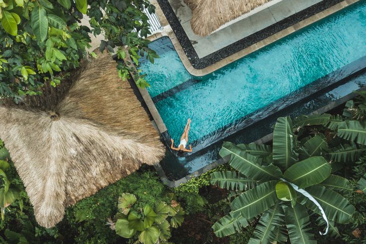 Aerial view of a woman in a tropical, luxury swimming pool