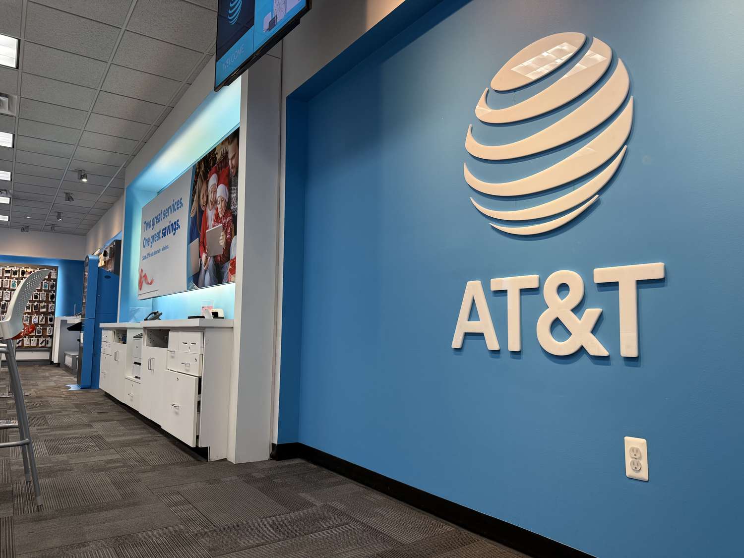 The AT&T logo is seen on a blue wall in an AT&T retail store.