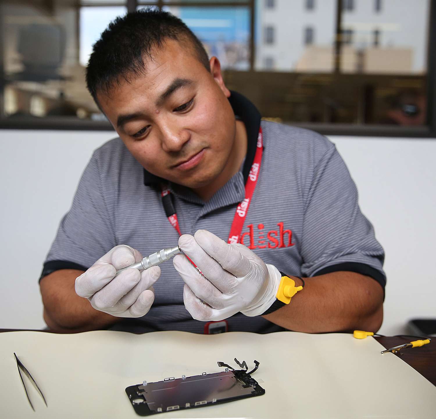 Dish employee Johnson Chuong takes apart an iPhone to fix a cracked screen on site in the Chronicle building in San Francisco, California, on wednesday, may 11, 2016.
