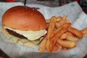 A cheeseburger and fries on a paper wrapper. 