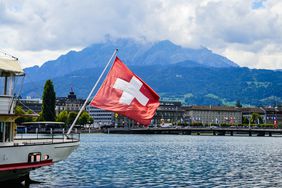 A view of a Swiss flag on a boat on lake Lucerne and Lucerne city in central Switzerland.