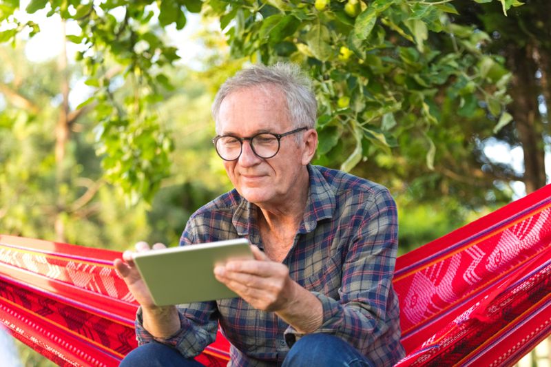 Retiree in hammock looking at a tablet