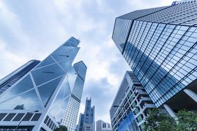 Bottom view of modern skyscrapers in business district against blue sky