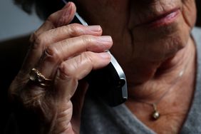 An older woman holding a cell phone to her ear.