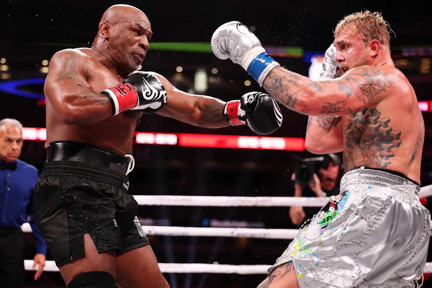Mike Tyson and Jake Paul throw punches during a boxing match.