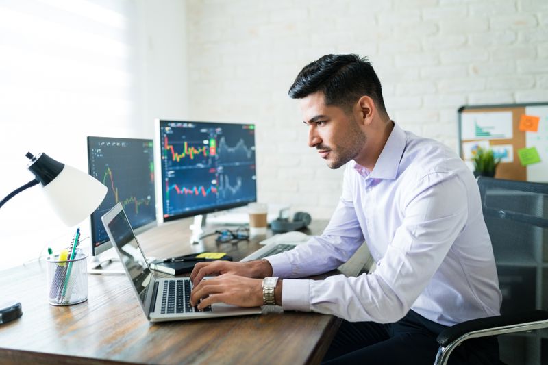 A trader uses technical chart analysis on a laptop to formulate a trading strategy.