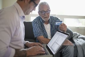 Son using a laptop to review his father's credit card bill showing several recurring payments.