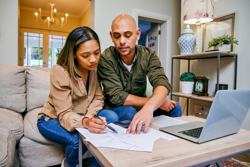Couple reviews finances while using laptop