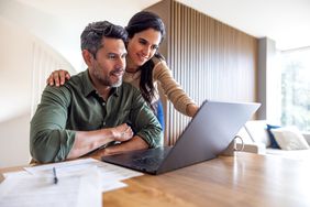 Two people looking at a laptop together while seated at a desk