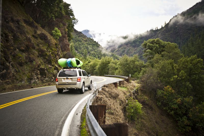 Car with Kayaks Driving Windy Road in Mountains