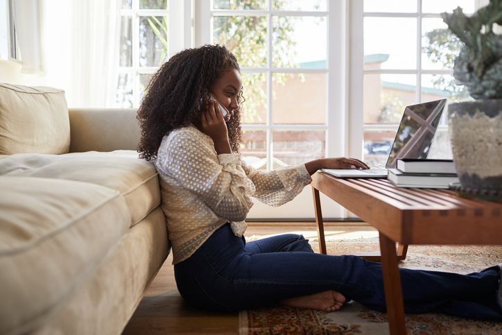 Woman looking at computer and using phone