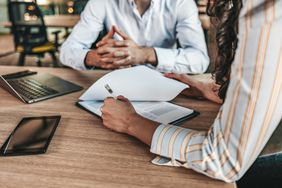 A divorcing couple signs paperwork to remove one person's name from their car insurance