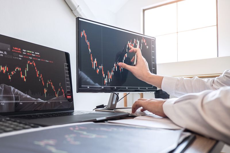 a person touching a computer monitor with a line graph