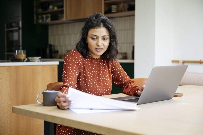 Woman with papers and computer at home