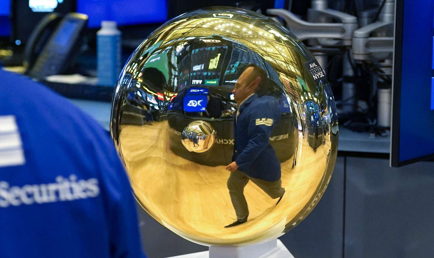 The reflection of a trader is shown in the bell on the floor of the New York Stock Exchange.