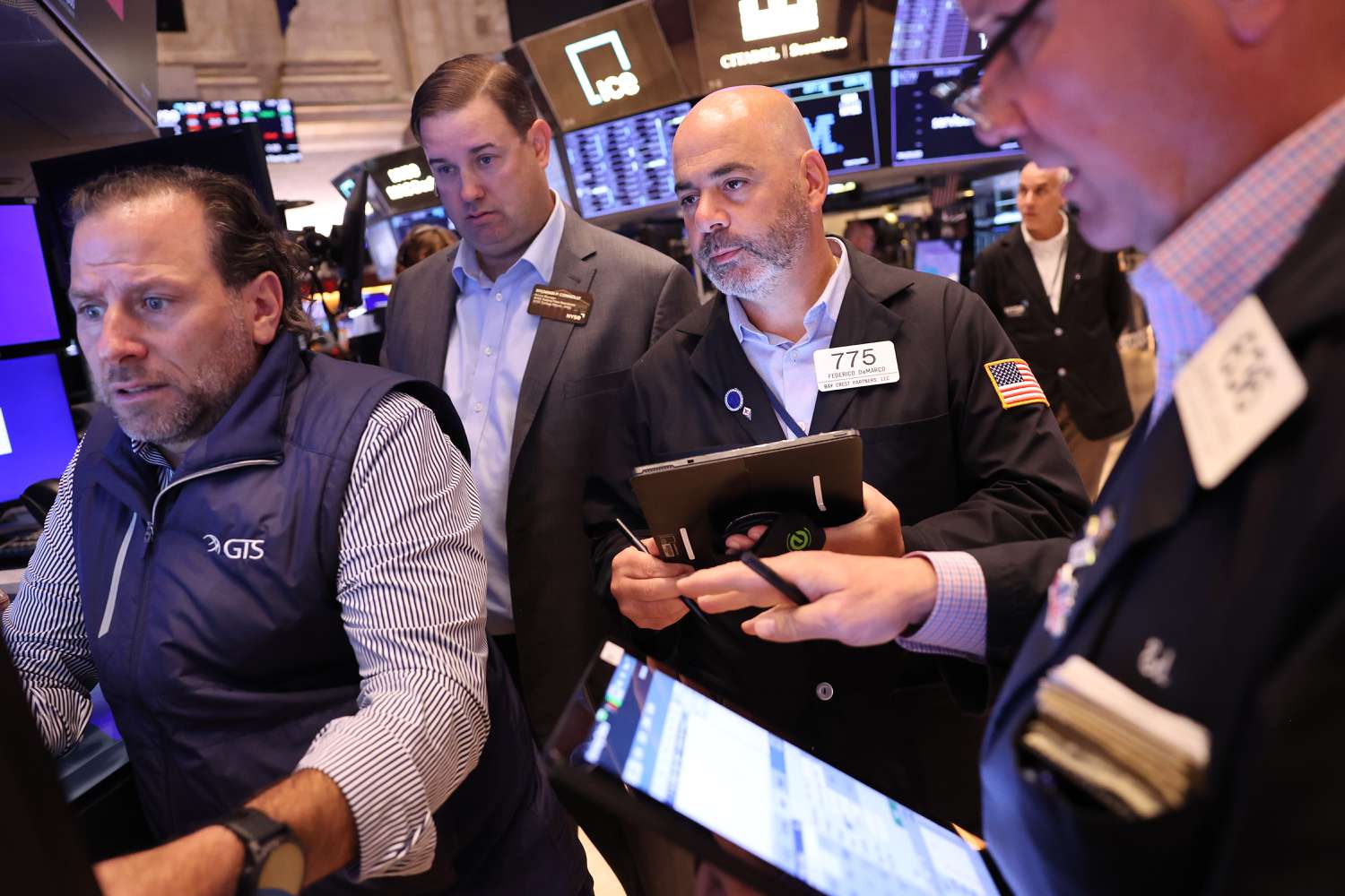 A group of stock traders stand on the floor of the New York Stock Exchange.