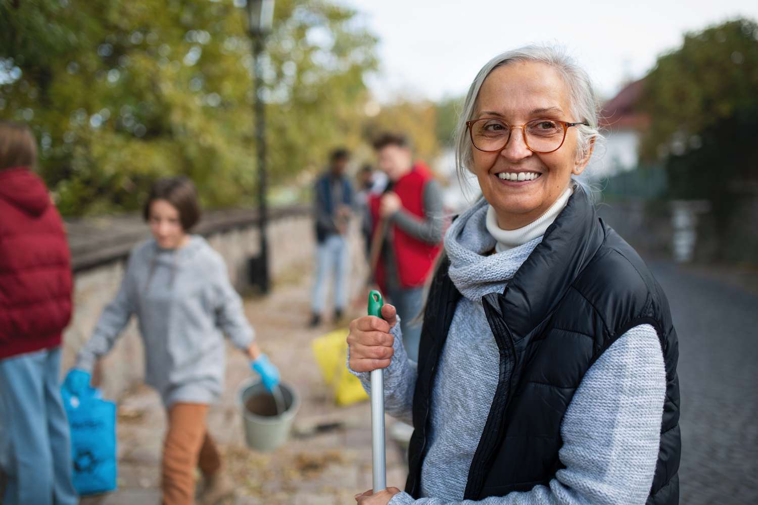 Senior woman volunteering to help clean street on a fall day.