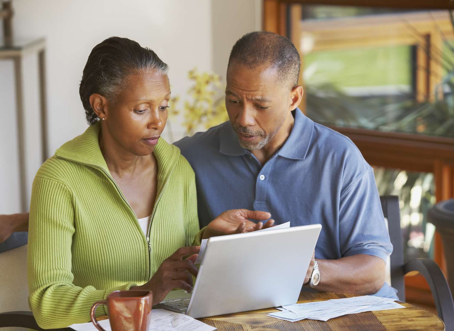 Couple in their 40s or 50s sitting at a table at home looking at mortgage rates on a laptop