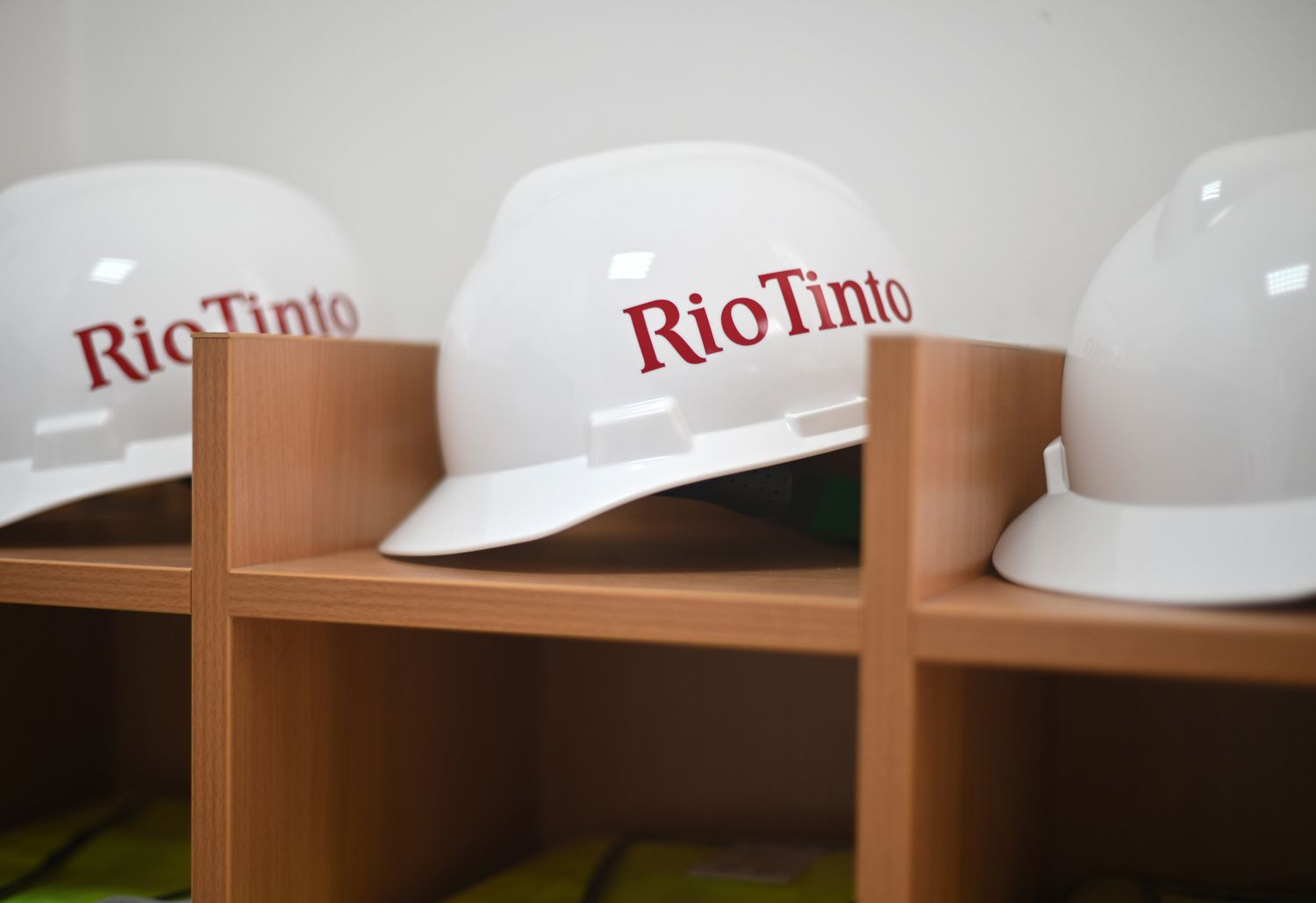 Three hardhats with the Rio Tinto logo written on the side sit on a shelf