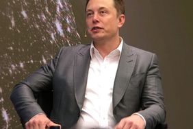 Elon Musk, seated and wearing a gray suit and white tailored shirt.