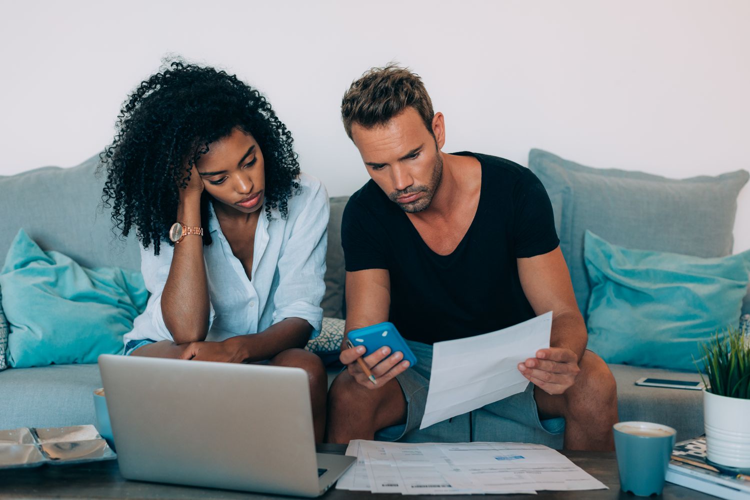 Interracial couple sitting on the couch looking stressed because of their credit locks.