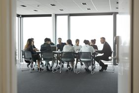 Co-workers having meeting with laptop in conference room