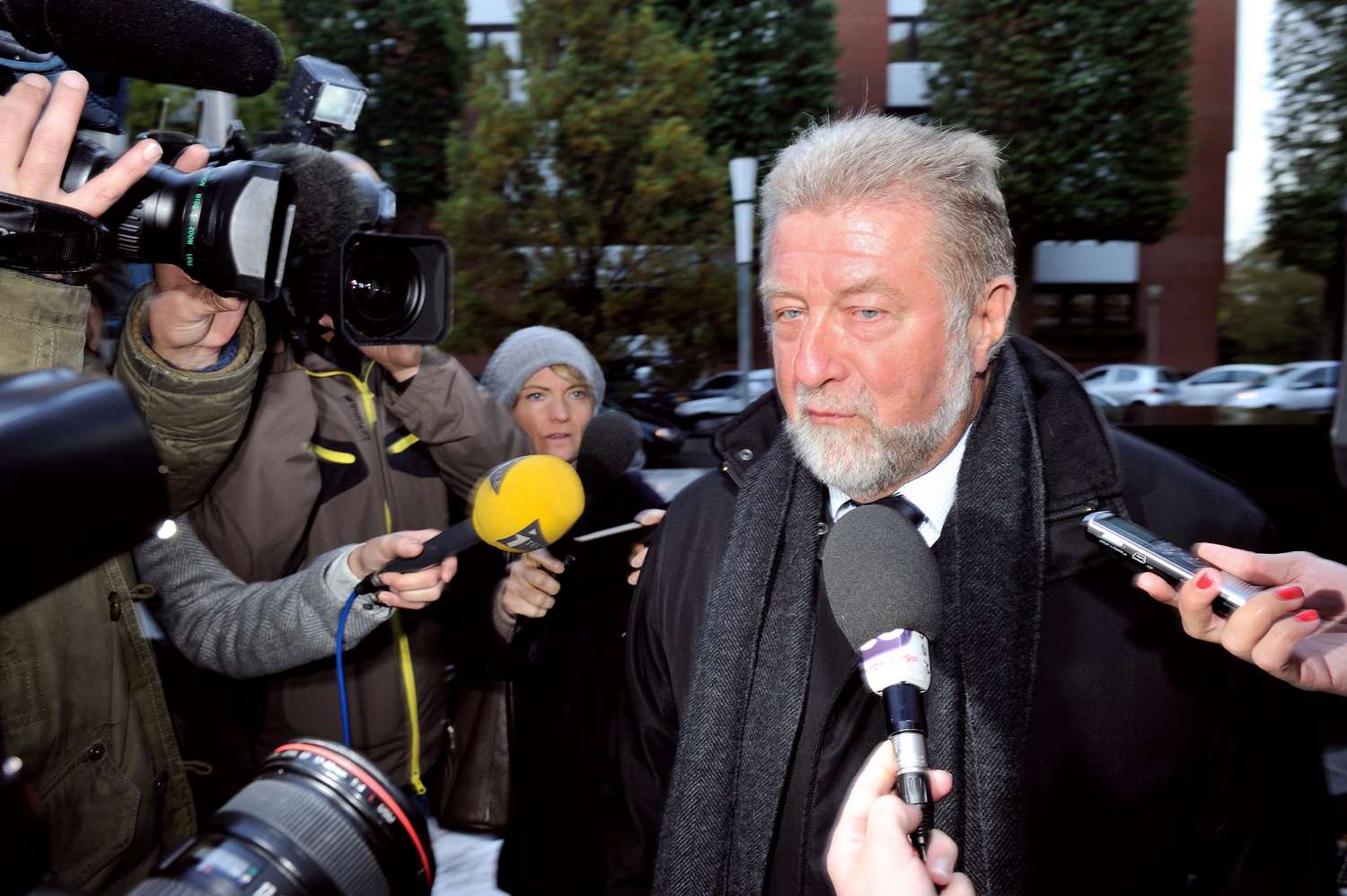 A corporate executive arriving at court and mobbed by press cameras
