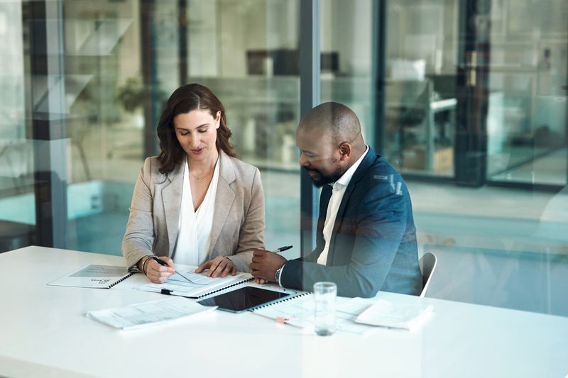 Two professionals review documents in an office.