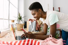 Female business owner working on a laptop and looking at a mobile phone