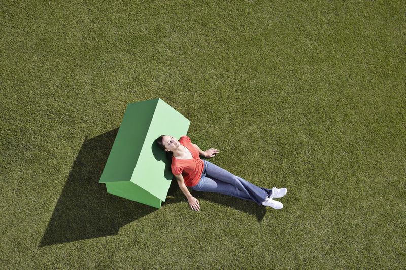 Woman leaning against small model house