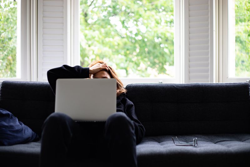 A woman looking stressed, sitting on a sofa.