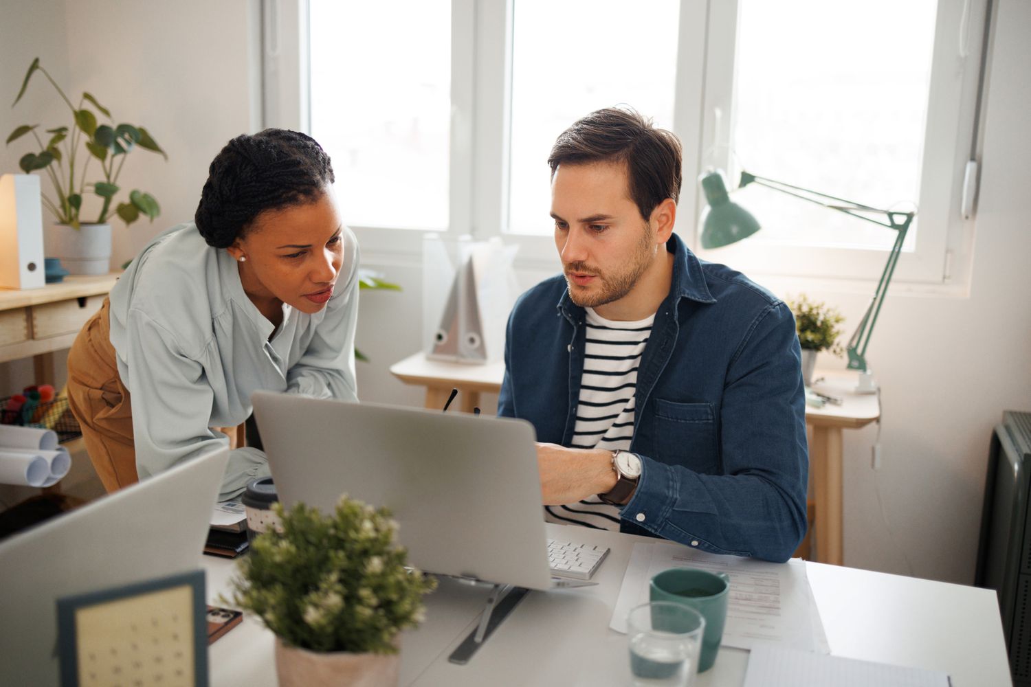 Colleagues collaborate in a home office setting.