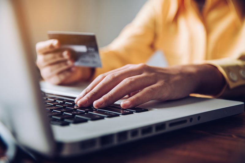 Cropped Hand of Businessman Holding Credit Card While Using Laptop in Office