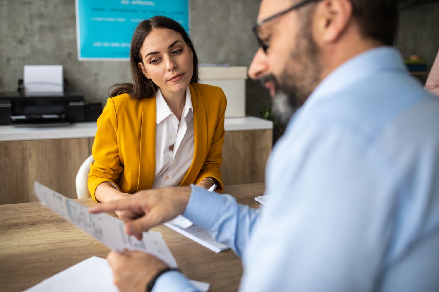 A woman and a man sit at a table looking over documents