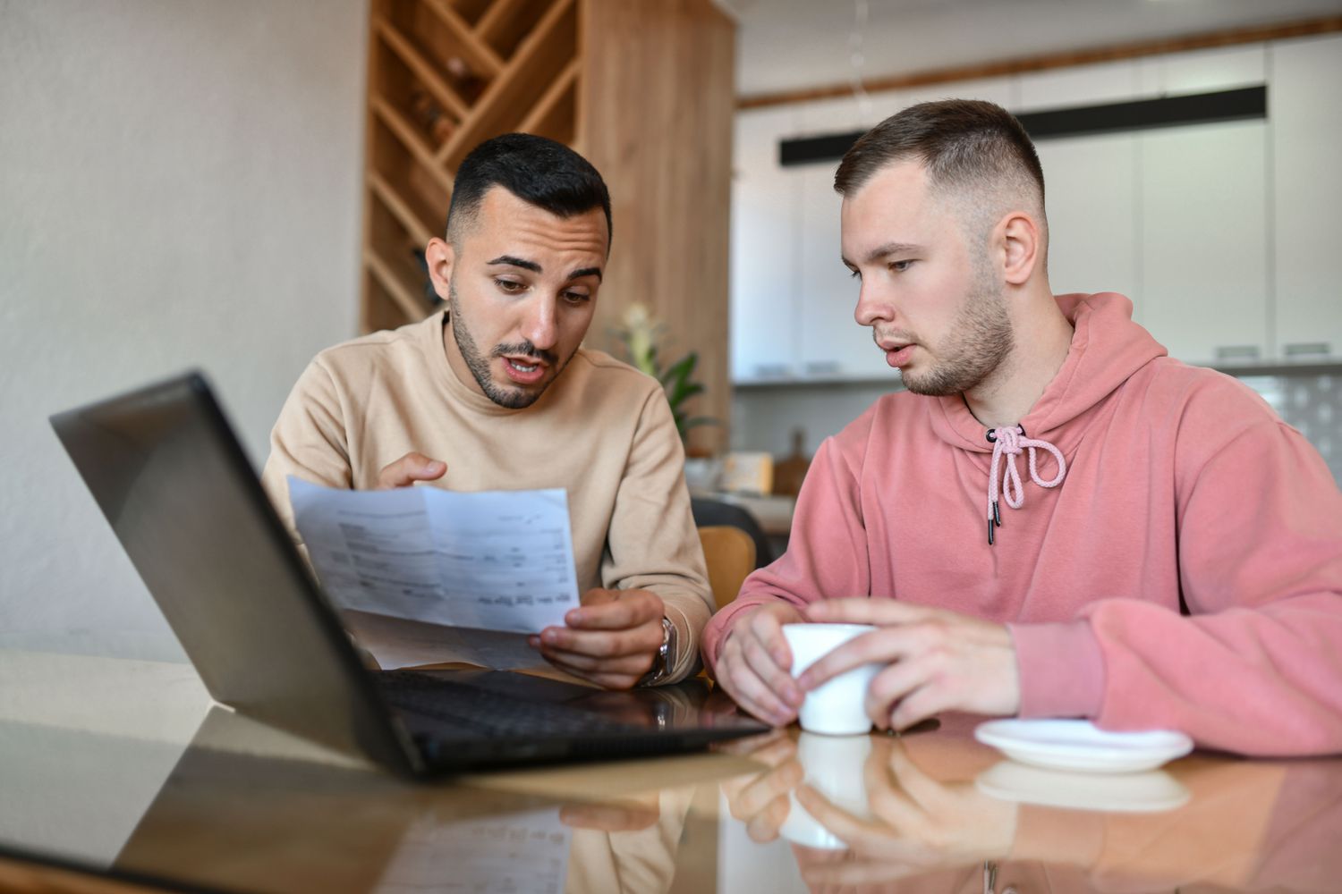 Two people doing paperwork at a laptop at home