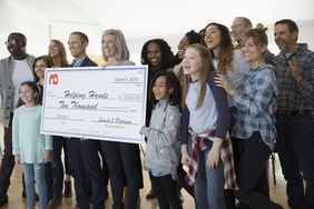 Enthusiastic community posing with large donation check