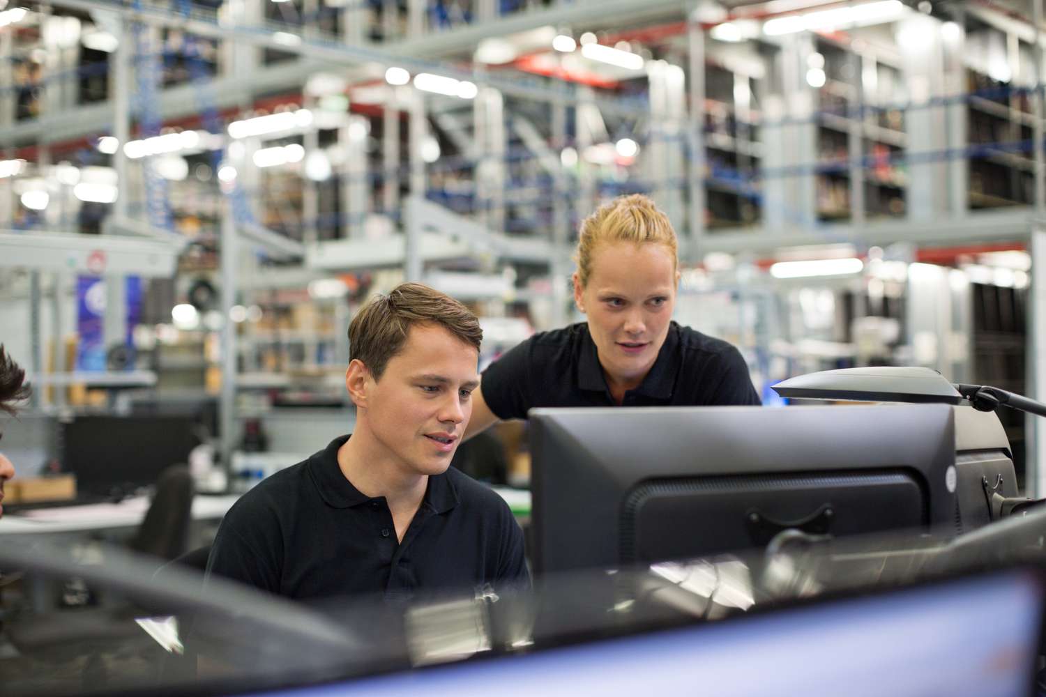 Man and woman looking at computer in logistics warehouse