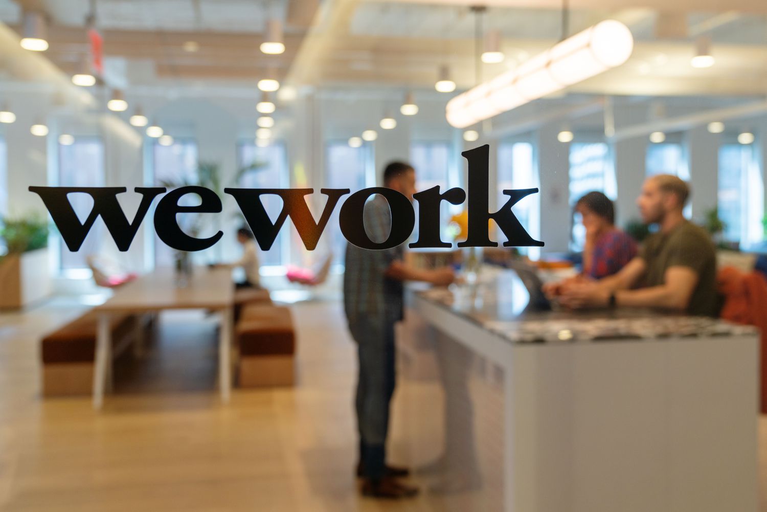 wework logo on glass door with people in the background