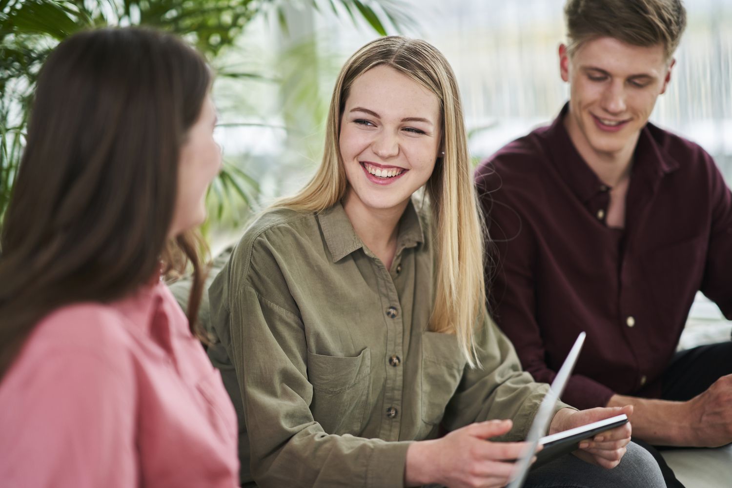 Three young interns smiling and talking