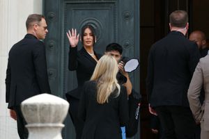 Kim Kardashian (center) waves as she arrives at the Assize Court for the trial during which she will testify over the 2016 robbery that saw her relieved of millions of dollars' worth of jewelry at gunpoint in Paris, on May 13, 2025.