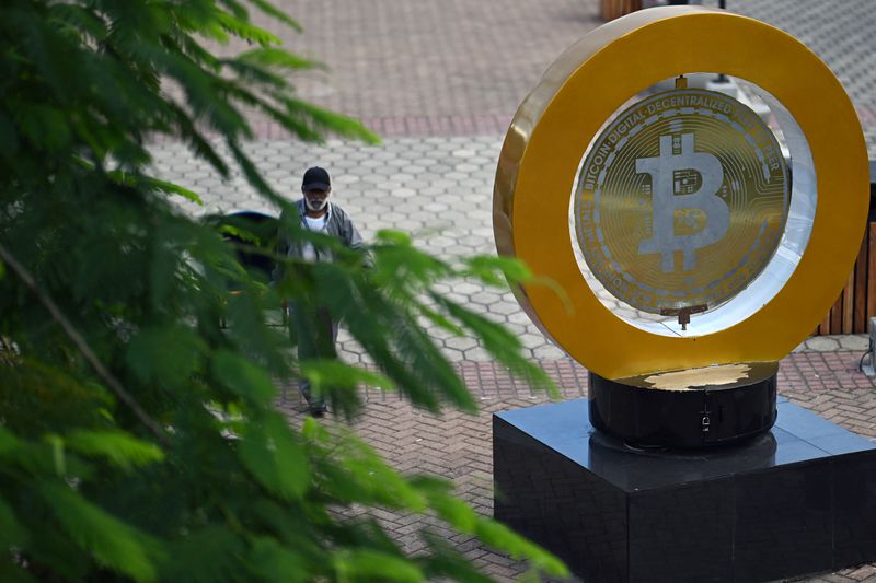A man walks past a bitcoin monument on a pedestal in El Salvador.