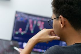 Young man analyzing a candlestick chart. 