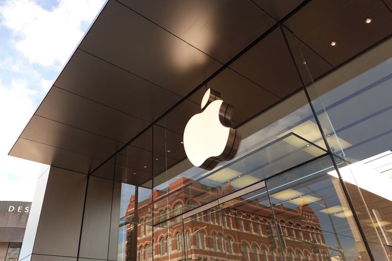 The Apple company logo hangs above an Apple retail store.
